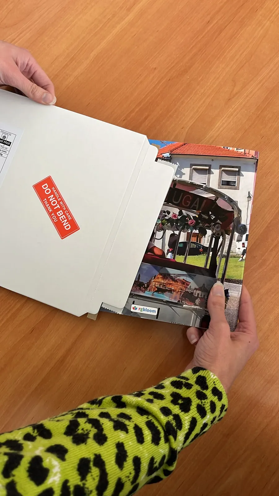 A finished book sliding into a white board envelope marked Do not bend