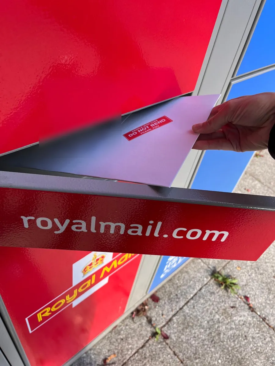 The envelope going into a Royal Mail post box