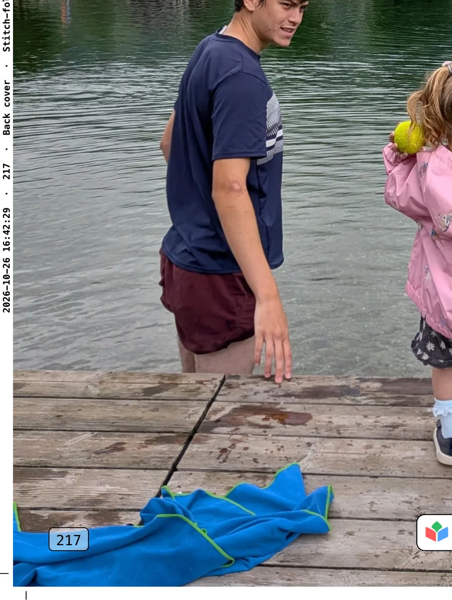 The bottom-left of the cover's print file: the back cover's photo of a lakeside jetty, crop marks in the corner, print code 217, and a line of small text up the edge