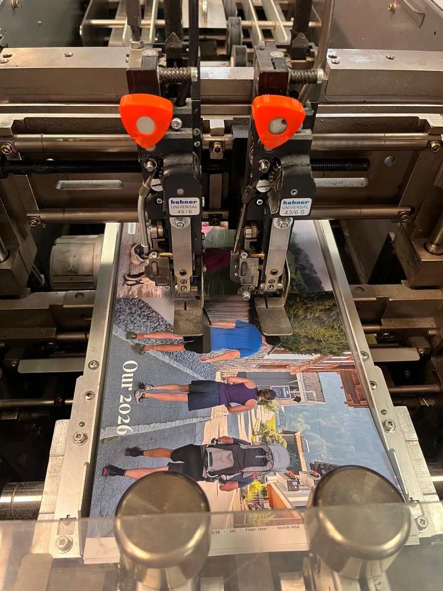 Two stitching heads above the open cover of the book