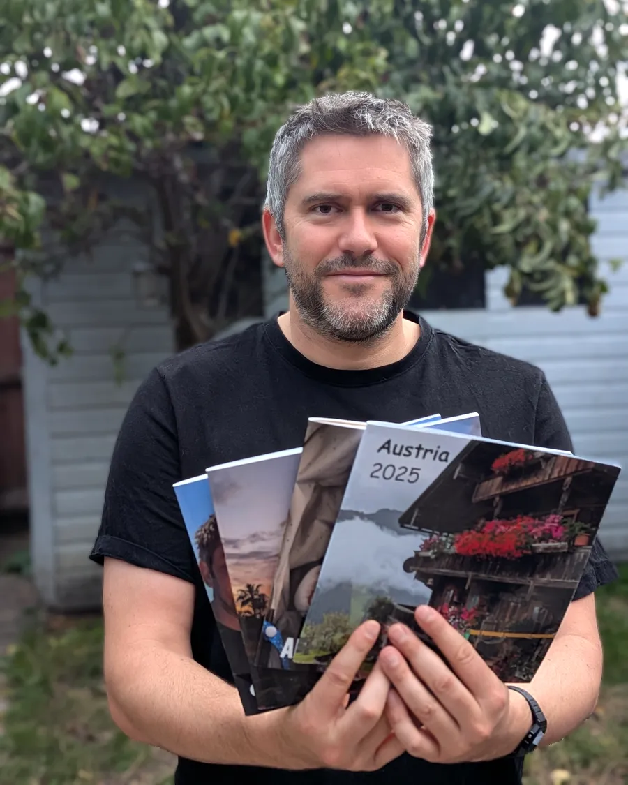 Jake Gordon holding a fan of RGBloom photo books, the front one titled Austria 2025